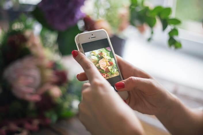 Jeune femme prenant les fleurs de la mariée en photo